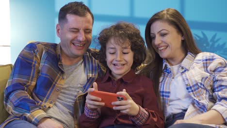 Young-mother-and-father-with-their-sons-resting-on-the-sofa,-spending-time-together.