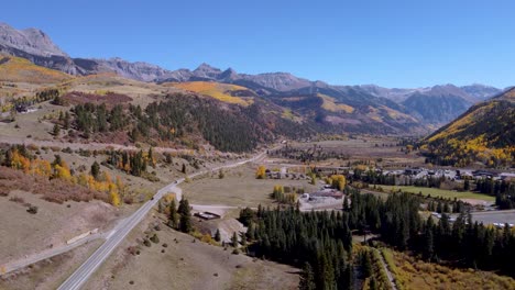 vista aérea de la autopista de un millón de dólares que corre hacia silverton, colorado, con álamos dorados alineando las montañas rocosas en un día sin nubes.