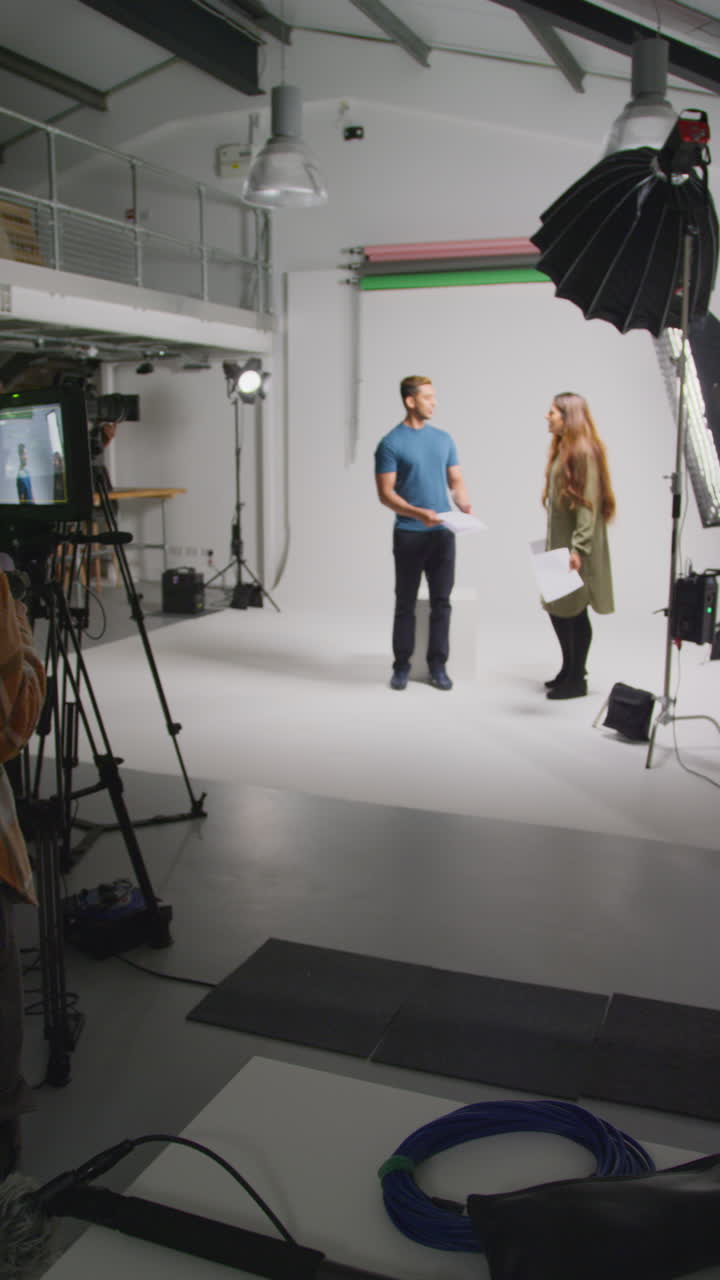 video vertical de actores con guiones en ensayo rodando una película o video en estudio con directora y equipo de filmación y viendo en el monitor