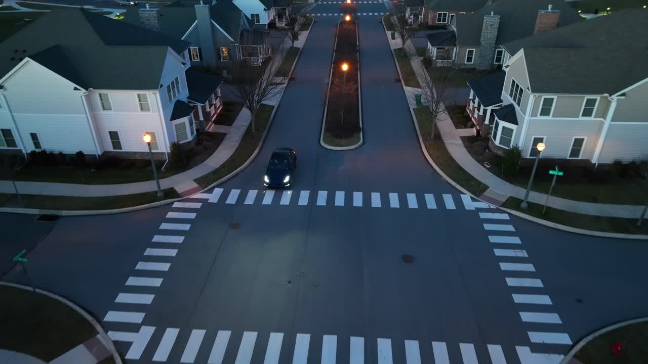 Electric car driving through modern American neighborhood at night
