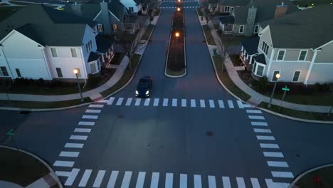 Electric-car-driving-through-modern-American-neighborhood-at-night