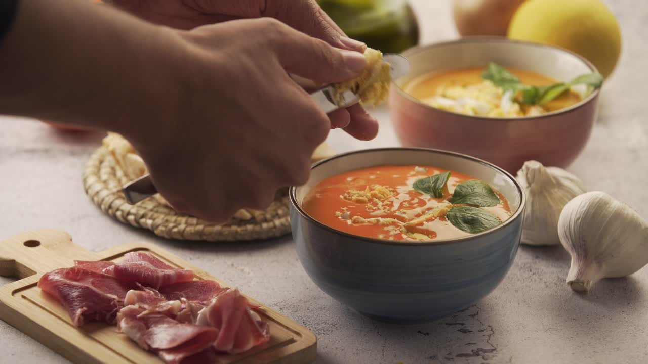 Serving salmorejo and egg in a bowl, with various ingredients around. Salmorejo is a tomato soup