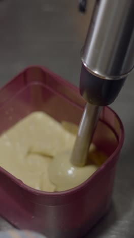 immersion blender mixing creamy substance in a container
