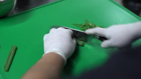 las manos del chef cortando cebolla verde en la tabla de corte verde, vista de arriba