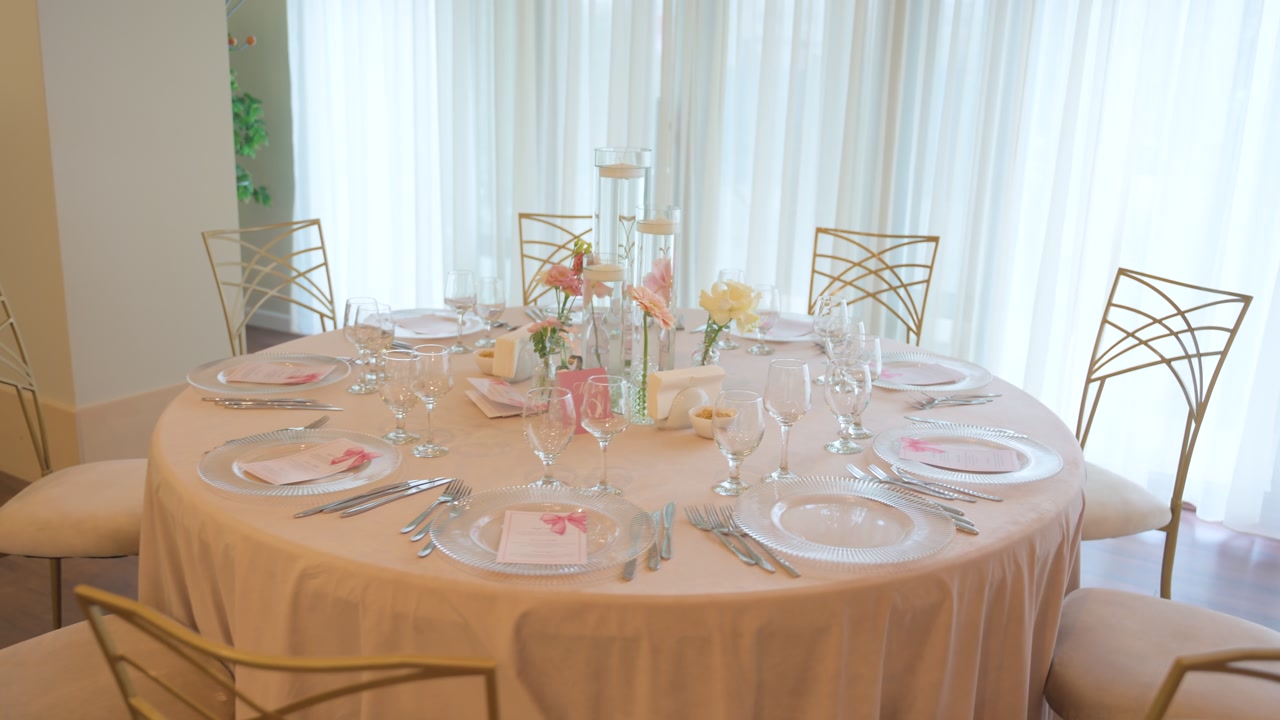Elegant round reception table prepared for a formal event, featuring a refined florals and tall glass candle holders