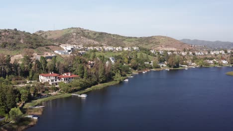 wide aerial dolly shot of lakefront homes along in the exclusive community of lake sherwood, california. 4k at 30 fps
