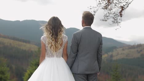 Lovely-caucasian-wedding-couple-newlyweds-family-bride-groom-stay-together-on-mountain-slope-hill