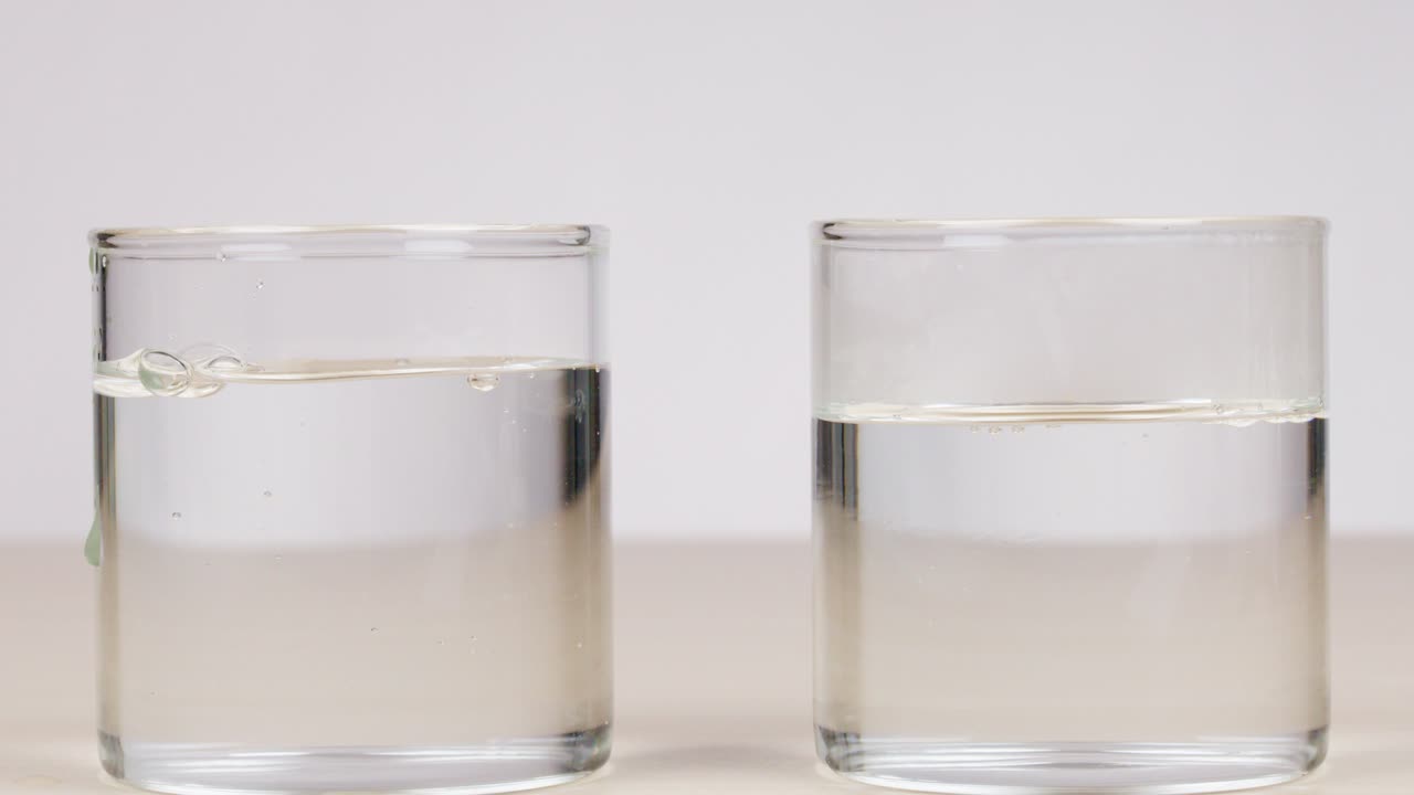 Two glasses filled with water at different temperatures, clear lighting, static camera, minimal background