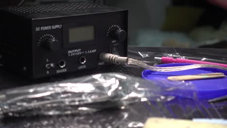 hand-held shot of a hand plugging in a cable into a tattoo machine