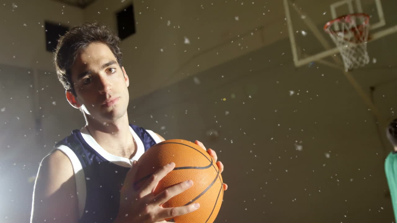 Holding basketball under spotlight, player standing with hoop in background