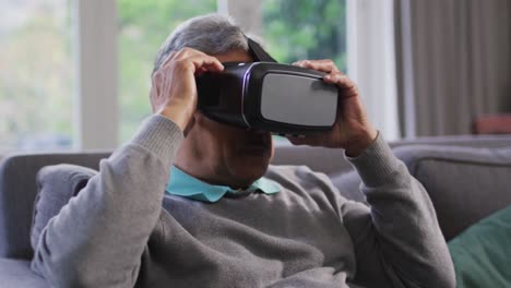 Happy-mixed-race-senior-man-wearing-vr-headset-and-having-fun-at-home