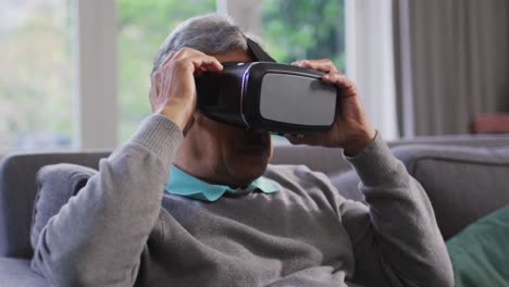hombre mayor de raza mixta feliz usando auriculares vr y divirtiéndose en casa