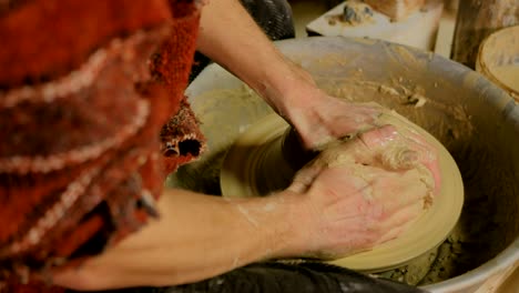 professional male potter working with clay on potter's wheel