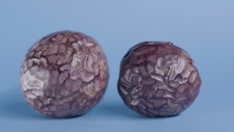dos frutas de la pasión enteras en una superficie azul aislada