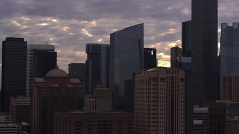 Drone-dolly-shot-moving-backwards-away-from-downtown-Houston,-Texas-during-sunset