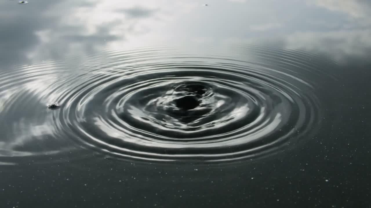 Flusso di goccioline che cadono su uno stagno calmo, formando increspature concentriche, a dimostrazione della scienza dei fluidi per il design.