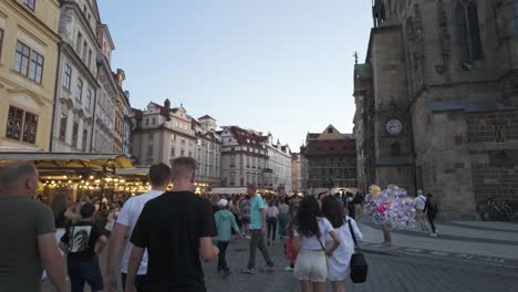 a lively crowd of tourists explores the historic old town square in prague during the early evening, capturing the vibrant atmosphere.