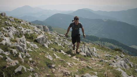 hiker climbin on the mountain raduha towards the camera, valley and other mountains visible in the background, partially cloudy