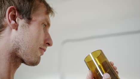 young man looks at elegant yellow wineglass in light room