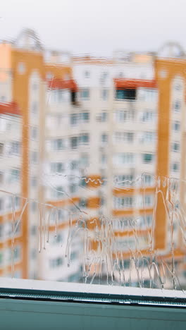 window cleaning brush making glass clean. house worker washing window with a special brush inside the room on urban background. vertical video