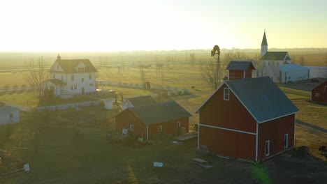 a drone aerial at dawn establishing shot over a classic farmhouse farm and barns in rural midwest america york nebraska