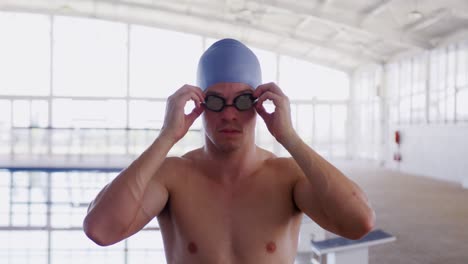 swimmer taking off his pool goggles and looking at camera