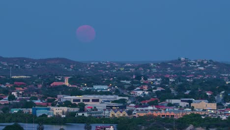 Langsames-Vergrößern,-Während-Der-Rot-violette-Supermond-Langsam-über-Willemstad-Curacao-Aufsteigt