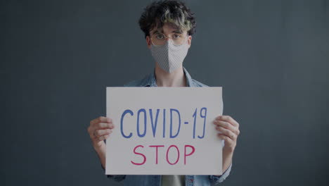 person holding a sign saying covid-19 stop