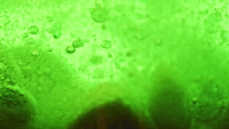 macro shot of big green bubbles setting on ground with many small sparkling bubbles