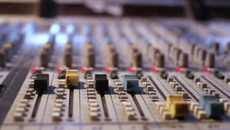 Dolly-shot-of-an-old-sound-board,-mixing-console-with-nobs-and-sliders