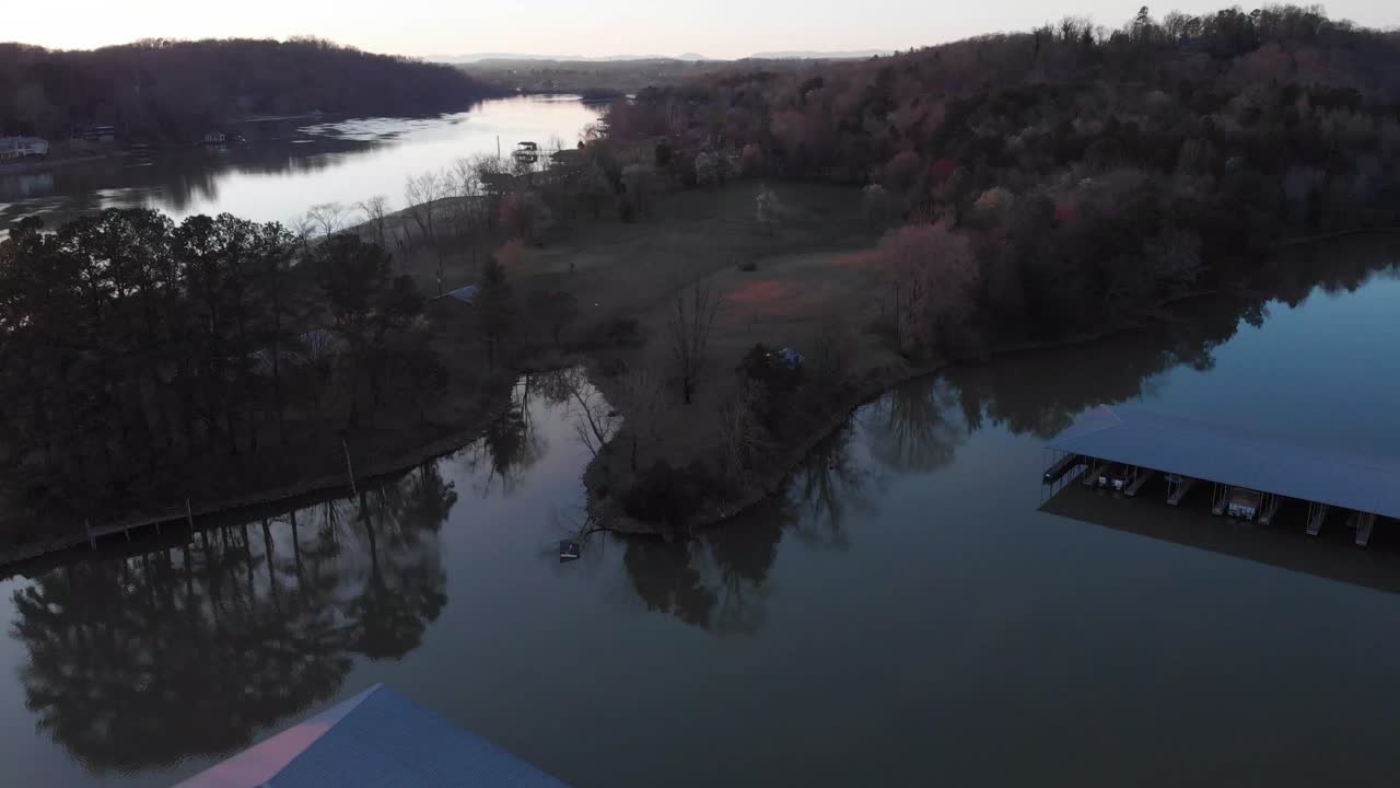 석양 아래에 육지와 보트 부두가 있는 호수 위의 공중 전망을 한 다음 보트 부두로 천천히 수위로 내려갑니다.