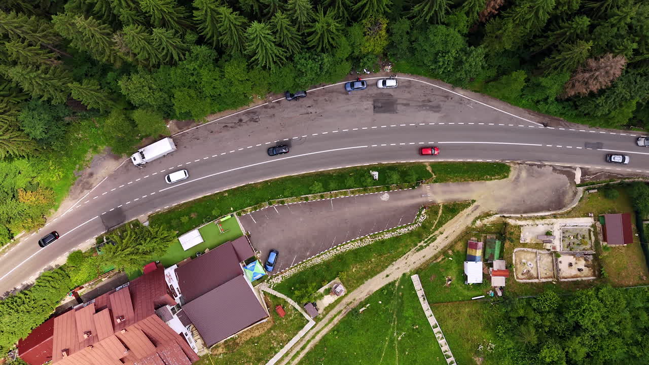 Traffic on curved mountain road in Romania. Cars and trucks moving on a curved mountain road near a village in Romania, view from above