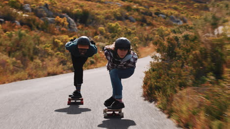 young friends longboarding together enjoying competitive race cruising fast downhill having fun riding skateboard wearing protective helmet summer vacation sport