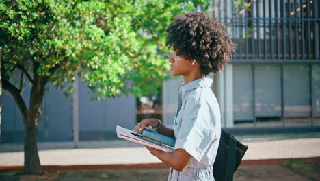 étudiante aux cheveux noirs marchant dans la rue tenant des livres en gros plan. fille allant à l'université
