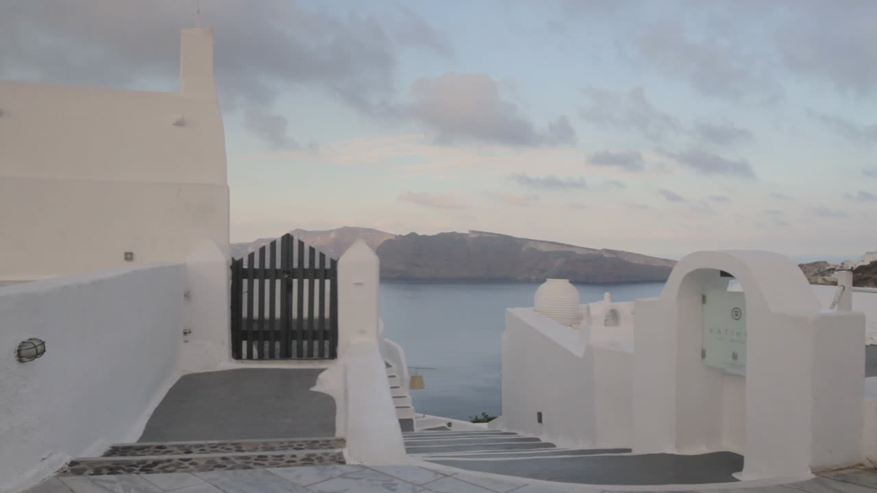toma de seguimiento de un callejón griego con vistas a la majestuosa vista de la caldera en santorini