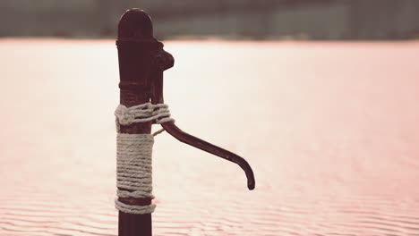 Rusty-old-metal-water-pump-on-sand-beach