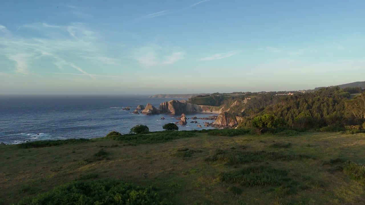 Kühe grasen auf einer Küstenwiese in Asturien im warmen Abendlicht.