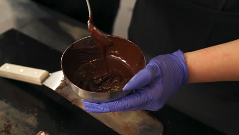 close up shot of man's hands playing with chocolate in a bowl with a spoon, interior