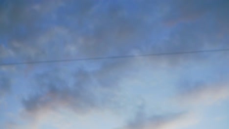 evening sky view with soft drifting clouds over urban setting featuring moving cars, parked vehicles, and faint outline of office buildings, capturing calm atmosphere of city life at dusk