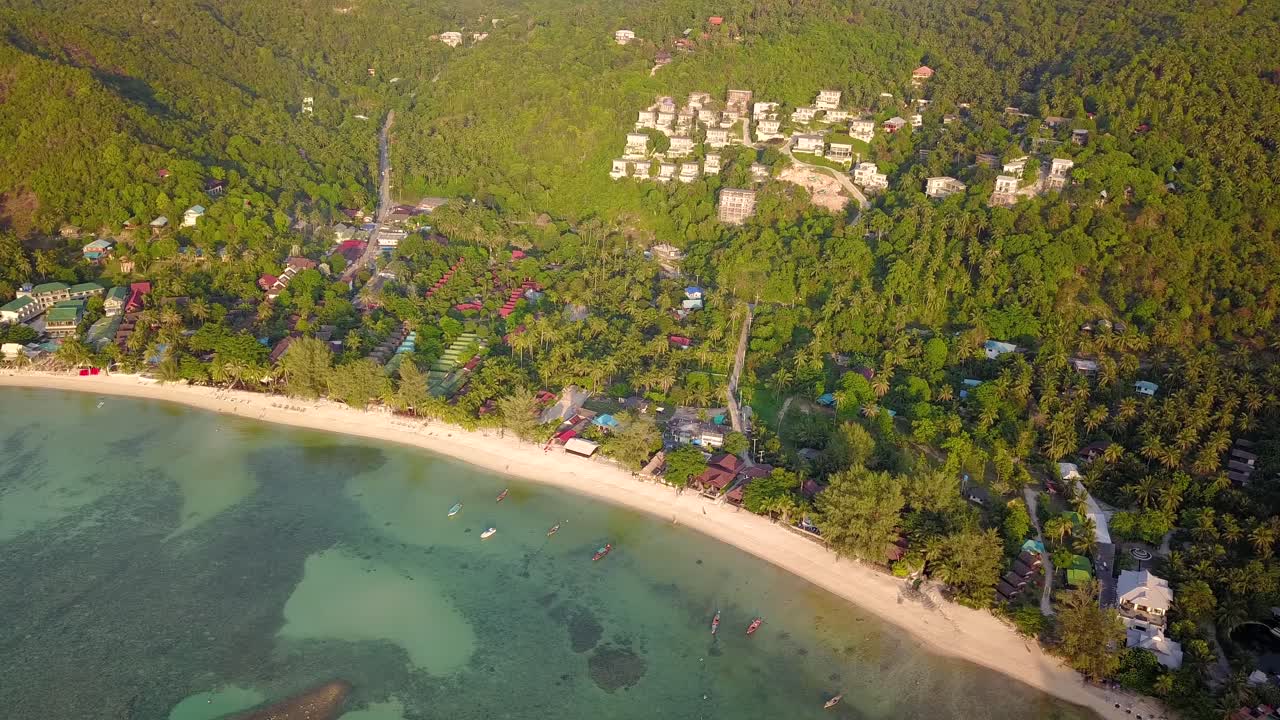 4k 공중 드론은 어선, 청록색 물, 산호 및 녹색 정글이 있는 태국 코팡안에 있는 샐러드 해변을 앞으로 밀어냅니다.