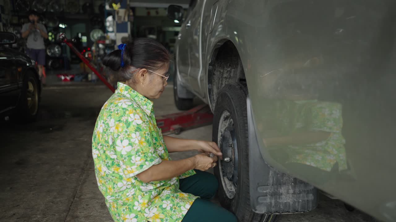 Woman Checking Tire in Car Repair Shop