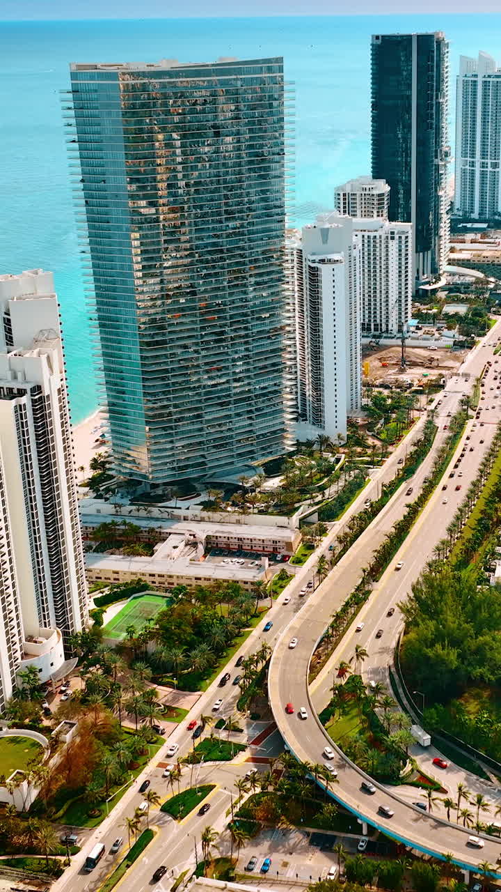 Drone che scende sopra l'autostrada a più corsie con diversi veicoli in movimento. Splendida Miami Beach, Florida, USA da una prospettiva aerea. Video verticale