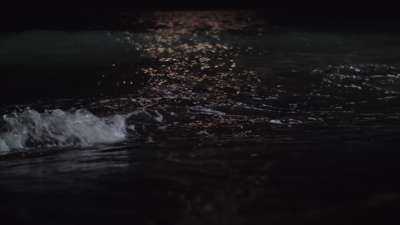 vista nocturna de las oscuras olas del mar rodando en la orilla