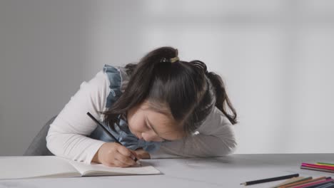 Foto-De-Estudio-De-Una-Joven-En-La-Mesa-Concentrándose-En-Escribir-En-El-Libro-Escolar-2