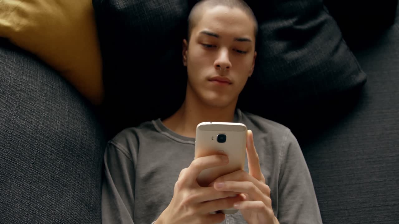 joven usando el móvil en casa 4k