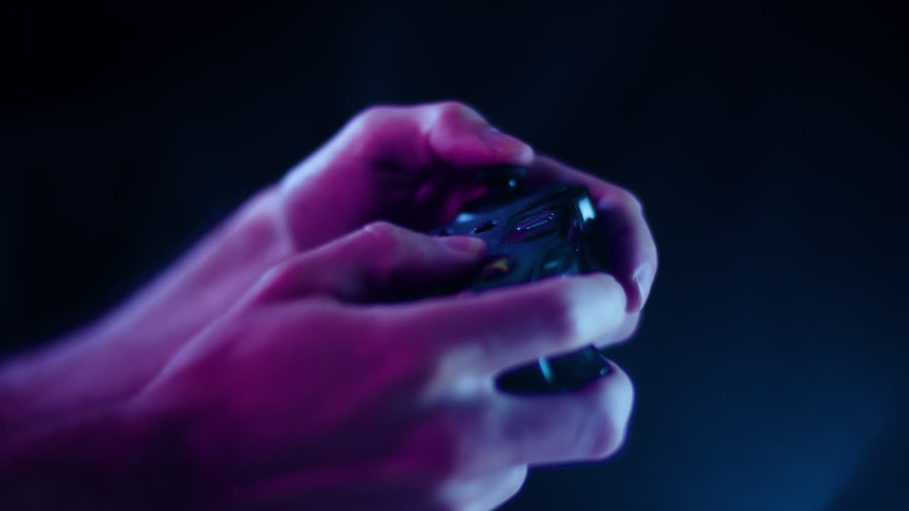 Playing video games in a darkened room with a black background close up on a controller joystick playing quickly blue lens flare for e sports