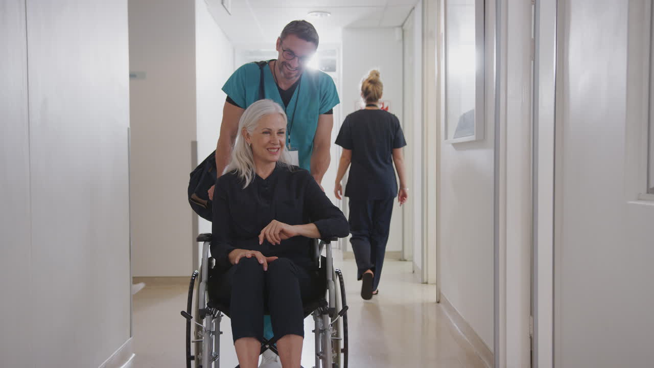 Männlicher Pfleger schiebt ältere Patientin im Rollstuhl, die aus dem Krankenhaus entlassen wird