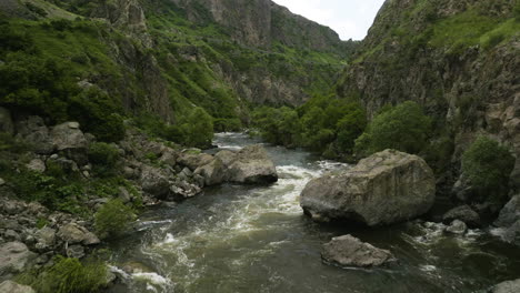 volando sobre el río mtkvari que fluye sobre imponentes montañas en la fortaleza de tmogvi, georgia