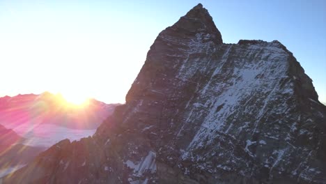hermoso amanecer sobre la cordillera distante con el famoso pico en forma de pirámide de matterhorn, monte cervino, mont cervin, en primer plano con acantilados rocosos empinados y nieve ligera
