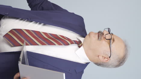 vídeo vertical del viejo hombre de negocios se relaja después de terminar su trabajo en la computadora portátil.